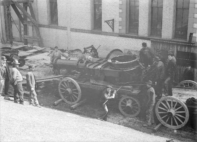 Construction workers loading pipe onto a horse-drawn wagon during work on the water main to the Broadway Pumping Station, South Toledo, about 1910. / Obreros cargan tubería sobre un carro de caballos durante las obras de la conducción de agua hacia la estación de bombeo de Broadway, sur de Toledo, hacia 1910.