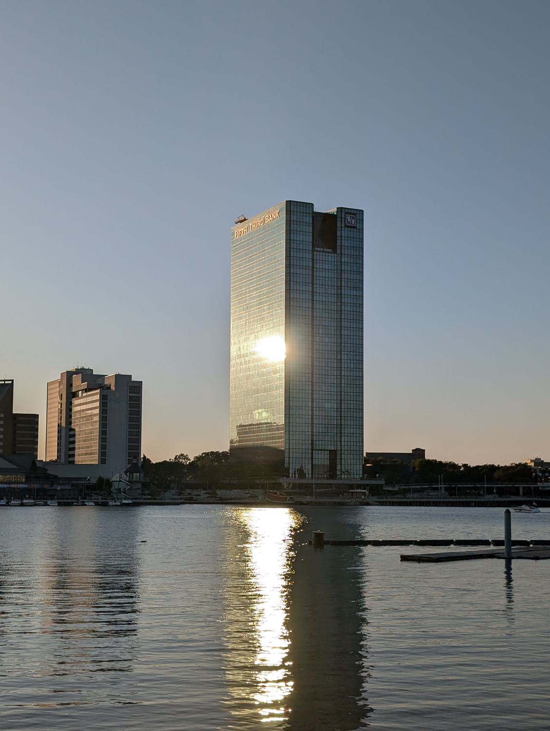 One SeaGate seen across the Maumee River at sunset, the low sun caught in its glass and thrown back down the water. / One SeaGate visto al otro lado del r&iacute;o Maumee al atardecer, con el sol bajo atrapado en su vidrio y reflejado sobre el agua.