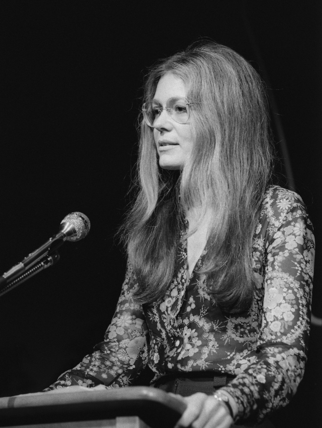 Gloria Steinem speaking at a lectern in 1975. / Gloria Steinem hablando desde un atril en 1975.