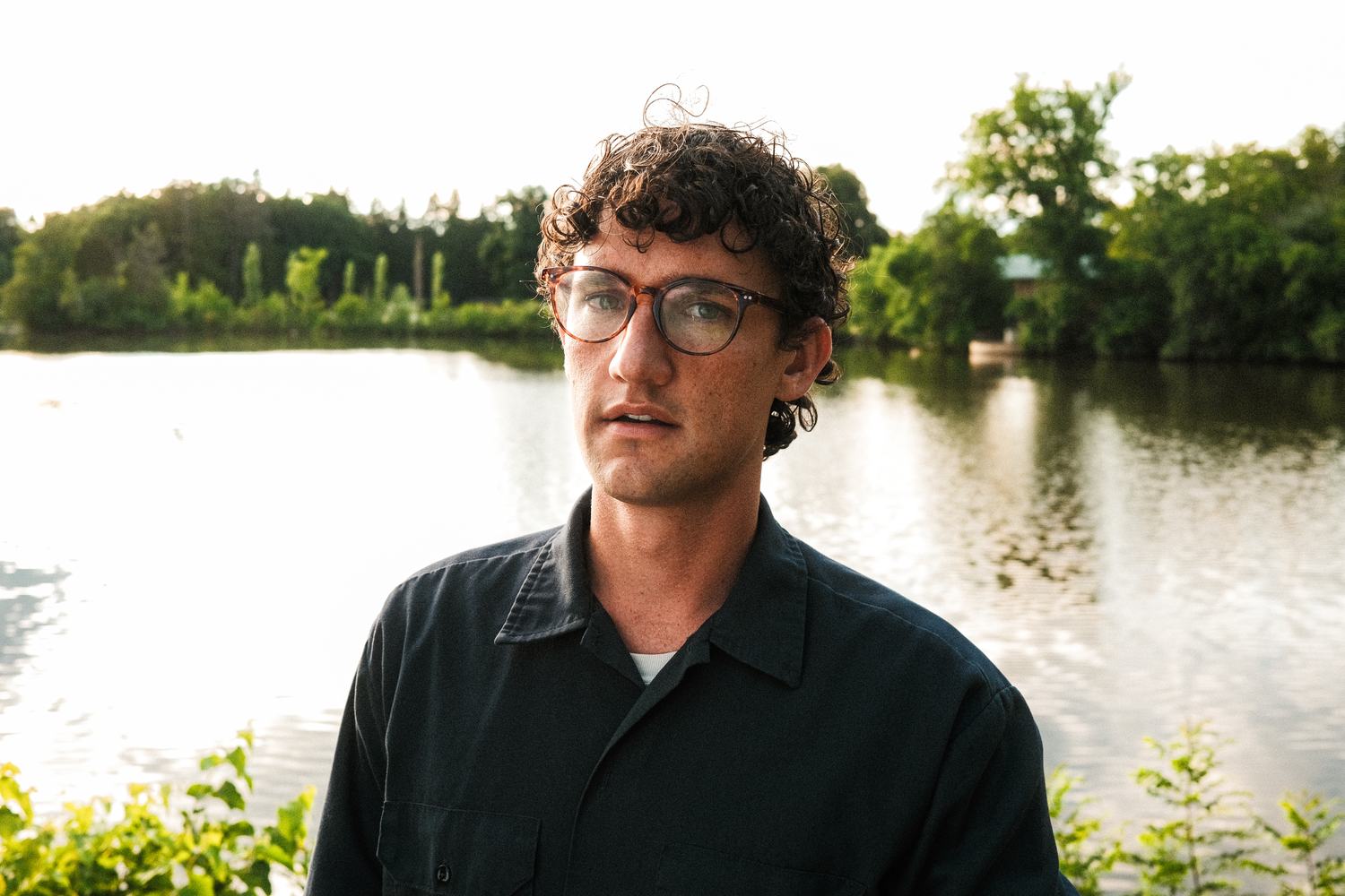 Christian Ohly, in glasses and a dark shirt, in front of a pond and trees