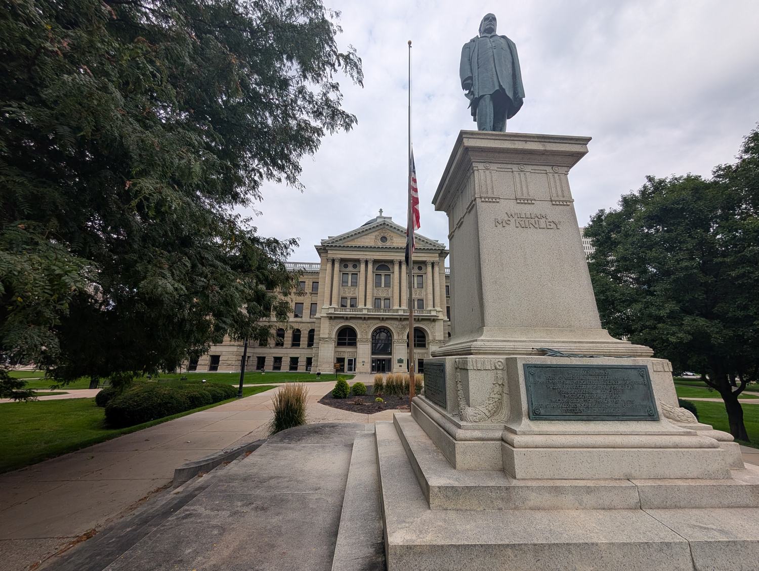 The bronze statue of President William McKinley on the lawn of the Lucas County Courthouse in Toledo, with the pedestal plaques in frame. / La estatua de bronce del presidente William McKinley en el jardín del Palacio de Justicia del condado de Lucas, en Toledo, con las placas del pedestal a la vista.